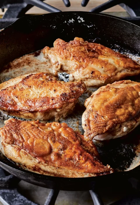 Ina Garten crispy chicken with golden skin-on breasts browning in butter in a cast-iron skillet