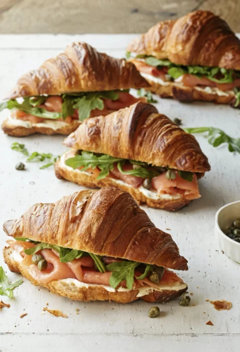 Ina Garten croissants with smoked salmon, mascarpone, capers and arugula on a white board