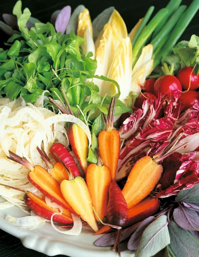 Ina Garten crudité platter with baby carrots, radicchio, endive, fennel, radishes, arugula and scallions arranged on a white platter