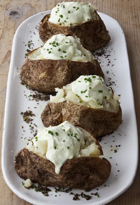 Ina Garten crusty baked potatoes with whipped feta and chives served on a long white platter