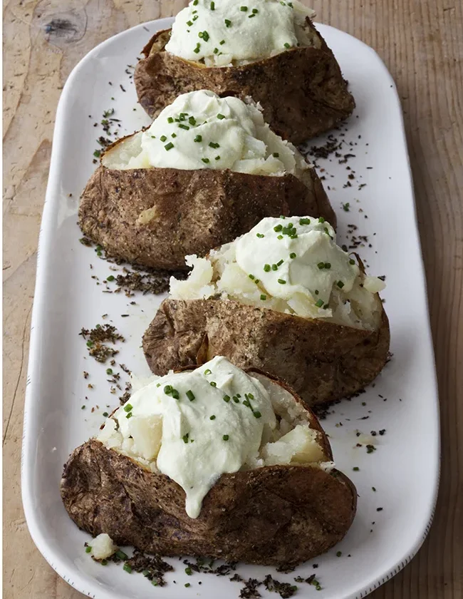 Ina Garten crusty baked potatoes with whipped feta and chives served on a long white platter