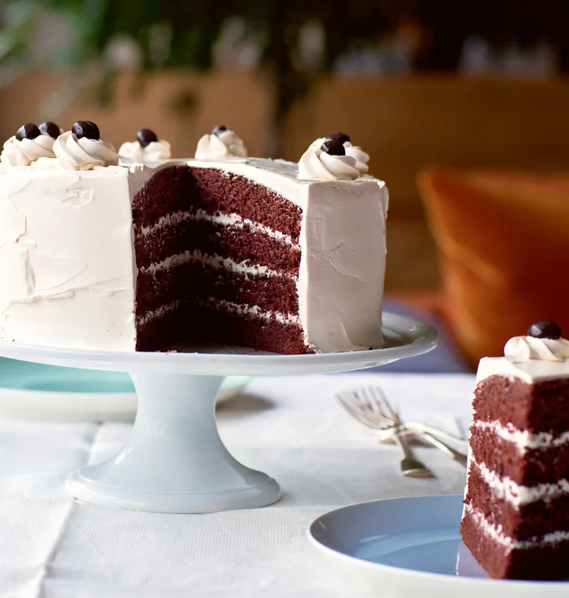 Ina Garten devil's food cake with coffee meringue buttercream cut to show four chocolate layers, topped with chocolate espresso beans