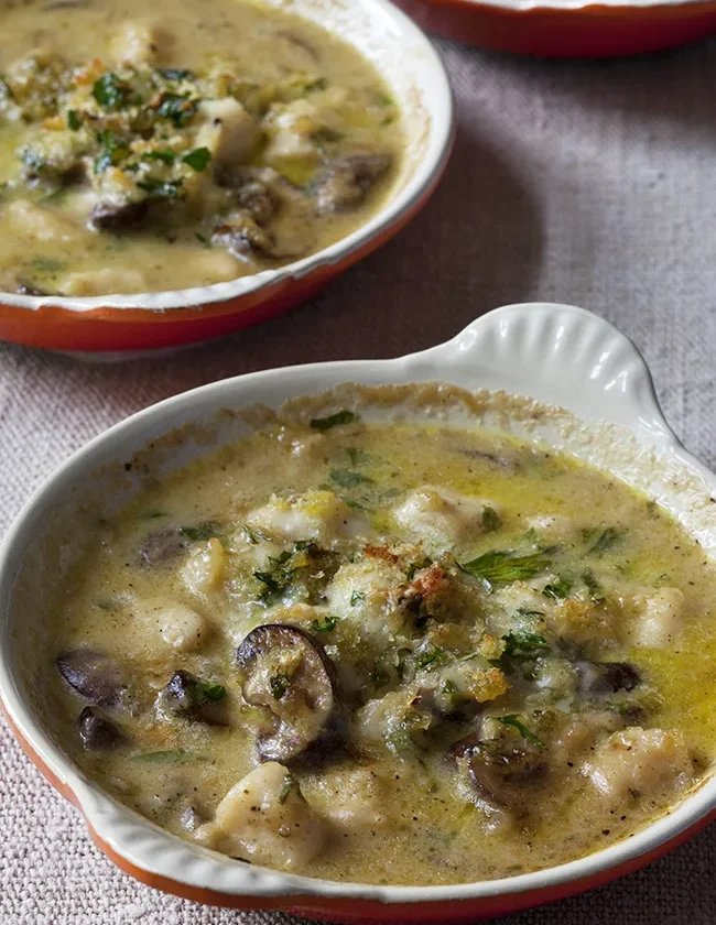 Ina Garten easy coquilles Saint Jacques in a white gratin dish with scallops, mushrooms and parsley in a creamy sauce