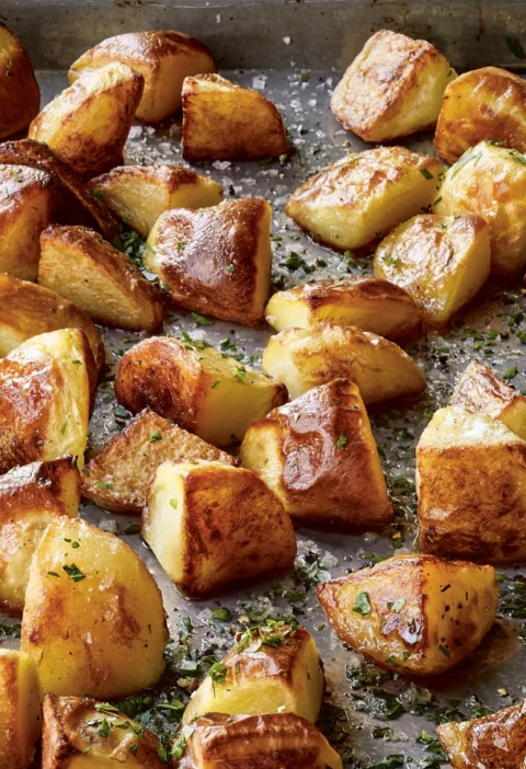 Ina Garten Emily's English roasted potatoes, golden crispy chunks sprinkled with sea salt and parsley on a sheet pan