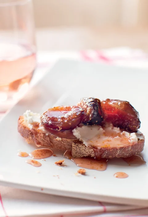 Ina Garten fig and goat cheese bruschettas with glossy fig preserves on toasted sourdough topped with creamy goat cheese on a white plate