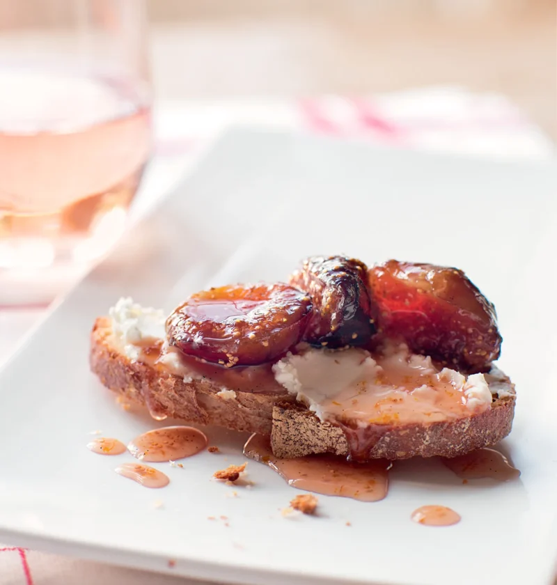 Ina Garten fig and goat cheese bruschettas with glossy fig preserves on toasted sourdough topped with creamy goat cheese on a white plate