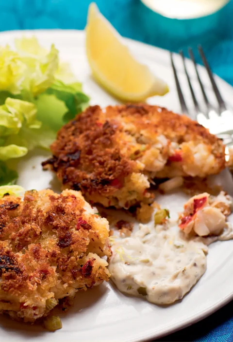 Ina Garten fish and lobster cakes golden brown with panko crust served with rémoulade sauce, lettuce and a lemon wedge