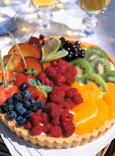 Ina Garten fresh fruit tart topped with raspberries, blueberries, strawberries, kiwi slices and orange segments in a golden tart shell