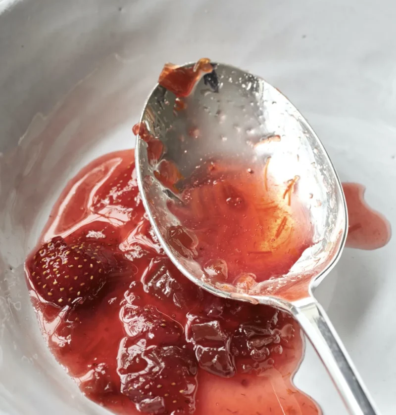 Ina Garten fresh strawberry rhubarb preserves in a white bowl with a silver spoon lifting a spoonful of jammy fruit