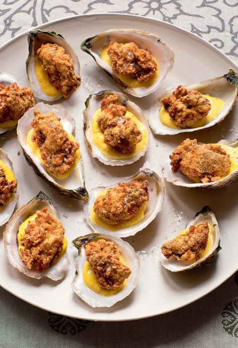 Ina Garten fried oysters with lemon saffron aioli served in oyster shells on a white platter with flaky salt