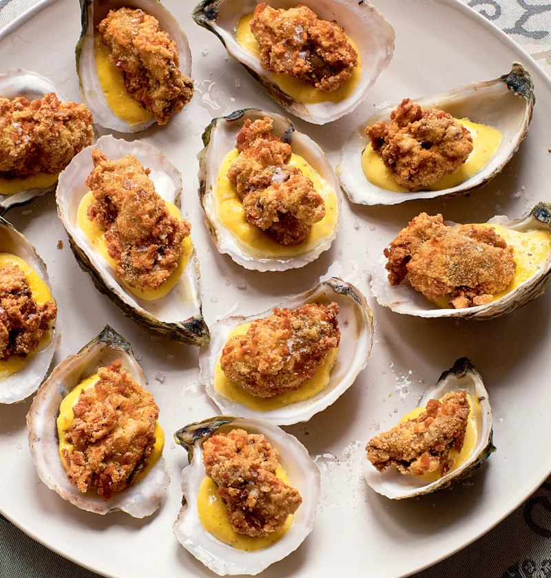 Ina Garten fried oysters with lemon saffron aioli served in oyster shells on a white platter with flaky salt