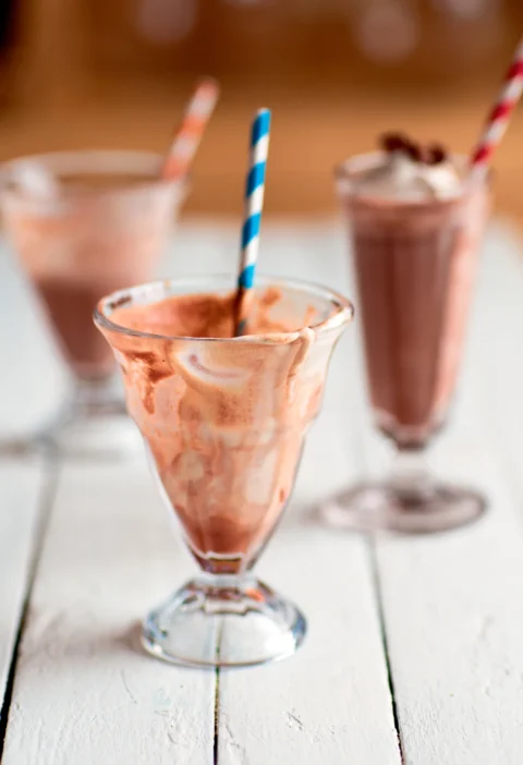 Ina Garten frozen hot chocolate in ice cream soda glasses with striped paper straws on a white wooden table