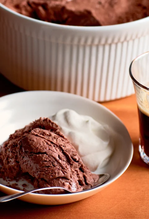 Ina Garten frozen mocha mousse scoop served in a white bowl with whipped cream next to a glass of espresso