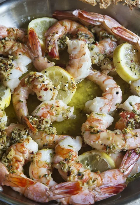 Ina Garten garlic and herb roasted shrimp in a pan with lemon slices, rosemary and garlic butter