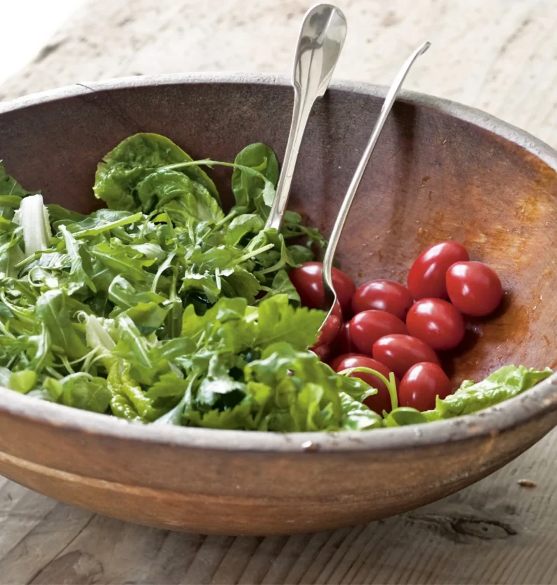 Ina Garten green salad vinaigrette tossed with fresh arugula in a rustic wooden bowl with grape tomatoes