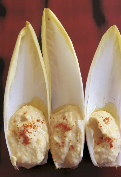 Ina Garten hummus spooned into three endive leaves and sprinkled with paprika