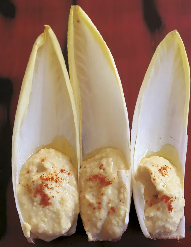 Ina Garten hummus spooned into three endive leaves and sprinkled with paprika