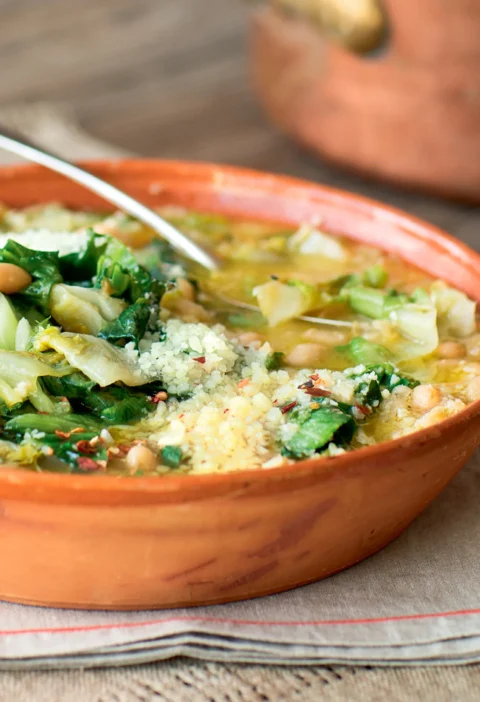Ina Garten Italian white beans and escarole in a terracotta bowl with grated cheese and red pepper flakes