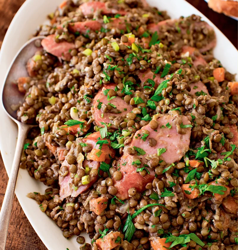 Ina Garten lentil and kielbasa salad with sliced kielbasa, diced carrots and parsley on an oval white platter