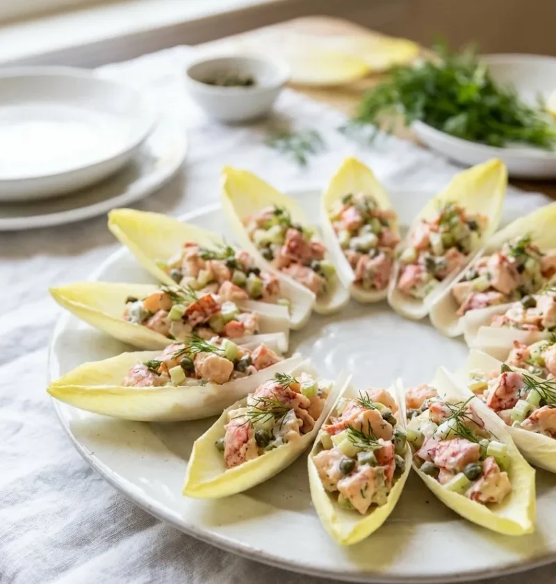 Ina Garten lobster salad in endive leaves topped with fresh dill arranged in a circle on a white platter