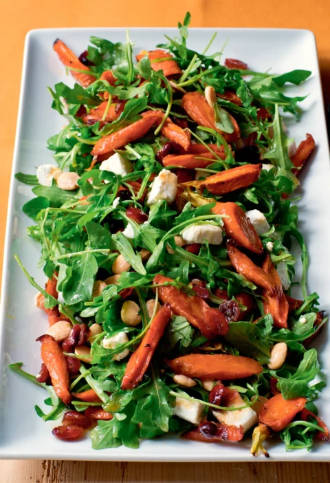Ina Garten maple-roasted carrot salad with arugula, goat cheese, dried cranberries and Marcona almonds on a white platter