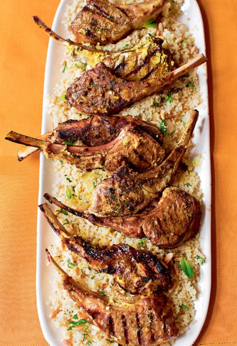 Ina Garten Moroccan grilled lamb chops with charred grill marks served over couscous with fresh mint on a long white platter