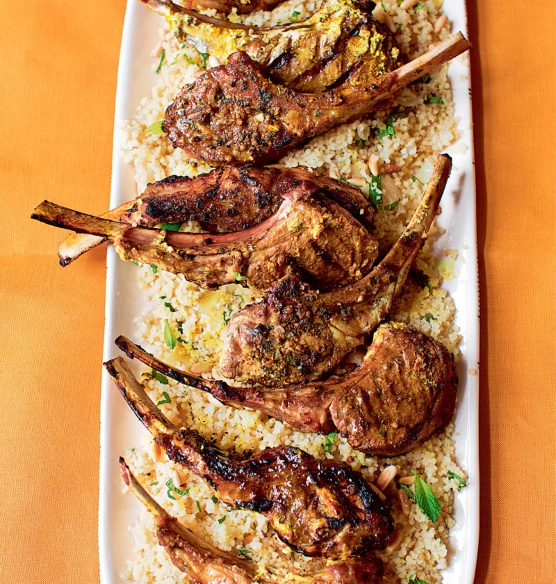 Ina Garten Moroccan grilled lamb chops with charred grill marks served over couscous with fresh mint on a long white platter