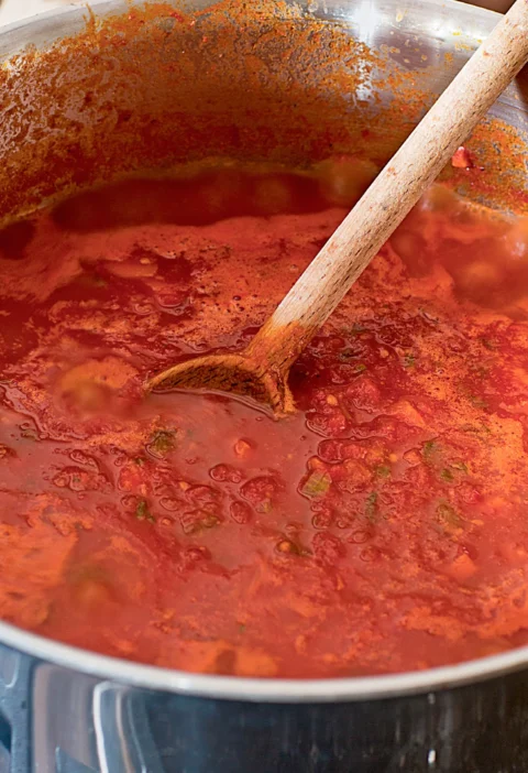 Ina Garten orecchiette with farm stand pasta sauce simmering in a pot with a wooden spoon