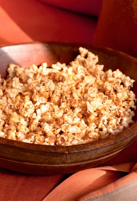Ina Garten parmesan and chipotle popcorn piled in a rustic wooden bowl with a golden orange seasoning