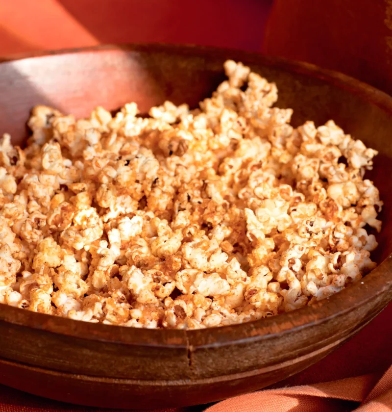 Ina Garten parmesan and chipotle popcorn piled in a rustic wooden bowl with a golden orange seasoning