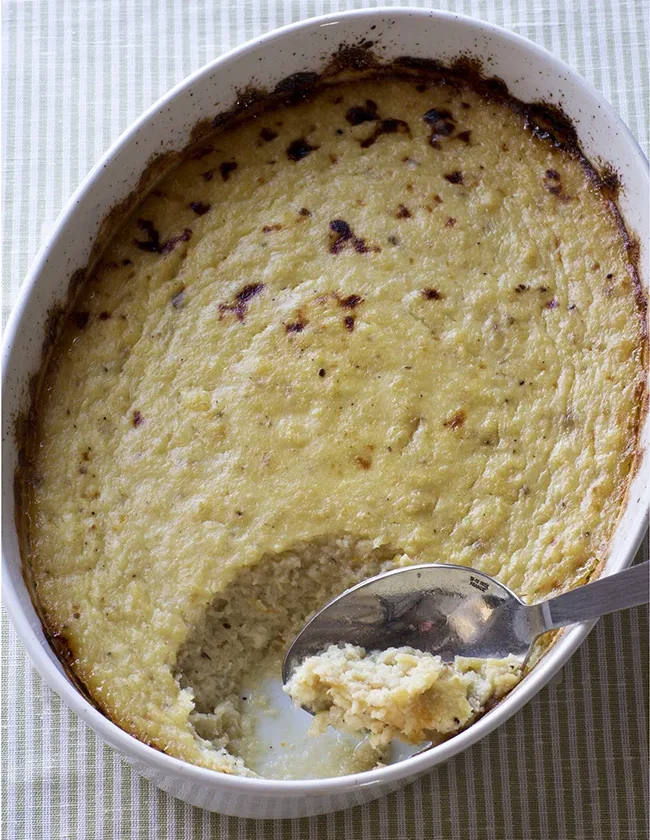 Ina Garten pear and parsnip gratin in an oval white baking dish with a spoonful scooped out