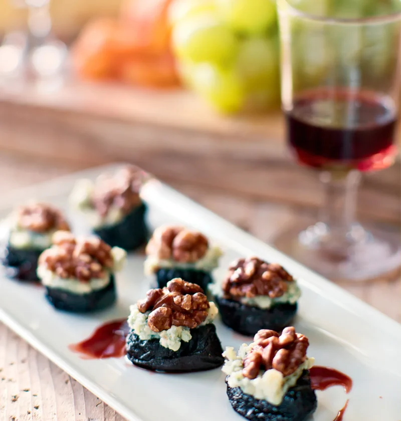 Ina Garten port wine prunes with stilton and walnuts on a white platter with a glass of red wine