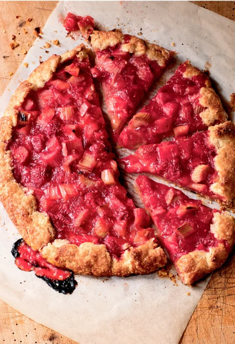 Ina Garten raspberry rhubarb crostata with a golden pleated crust cut into slices on parchment paper