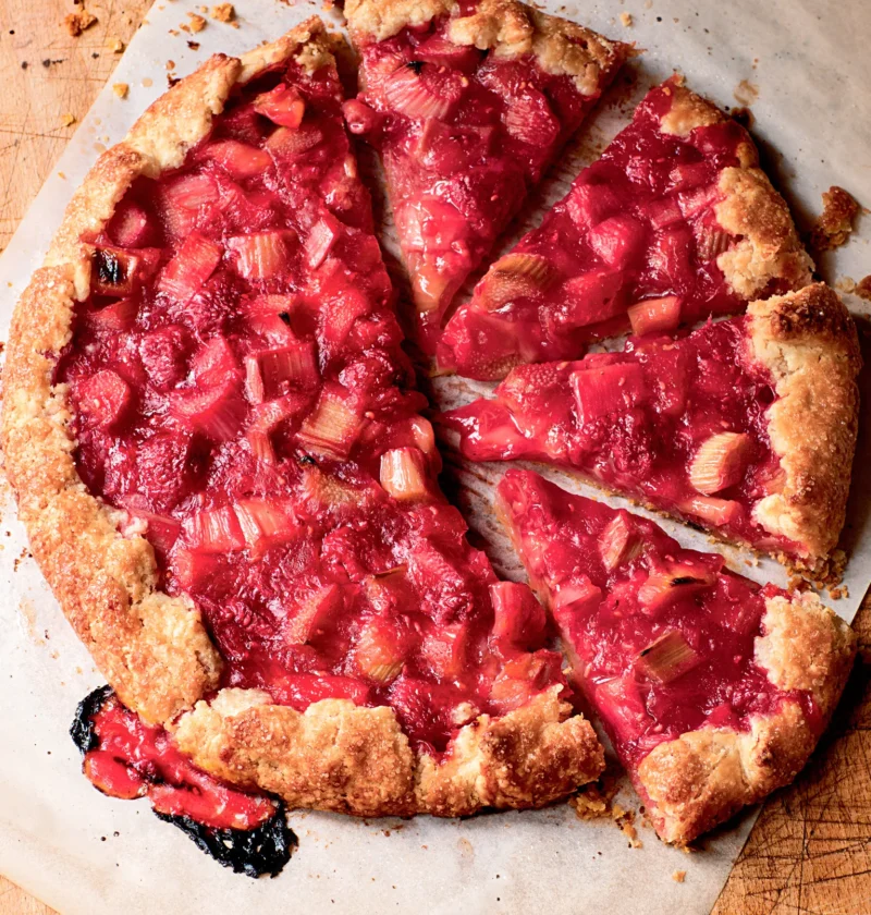 Ina Garten raspberry rhubarb crostata with a golden pleated crust cut into slices on parchment paper