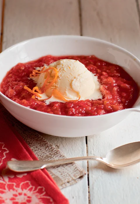 Ina Garten raspberry roasted applesauce in a white bowl topped with a scoop of vanilla ice cream and orange zest