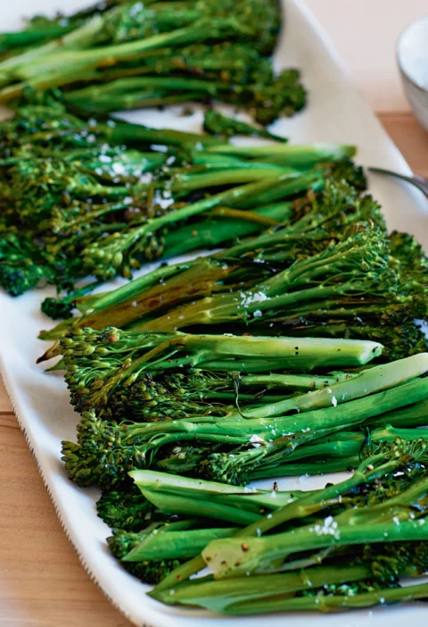 Ina Garten roasted broccolini with crisp tips and flaky salt served on a long white platter