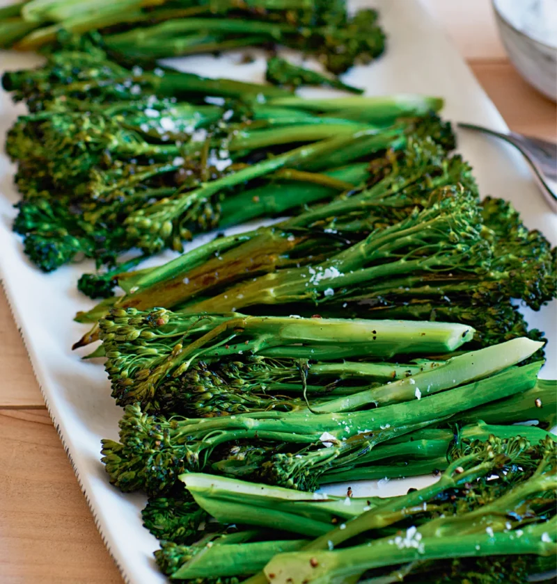 Ina Garten roasted broccolini with crisp tips and flaky salt served on a long white platter