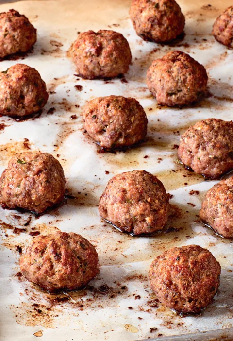Ina Garten roasted Italian meatballs browned on a parchment-lined sheet pan