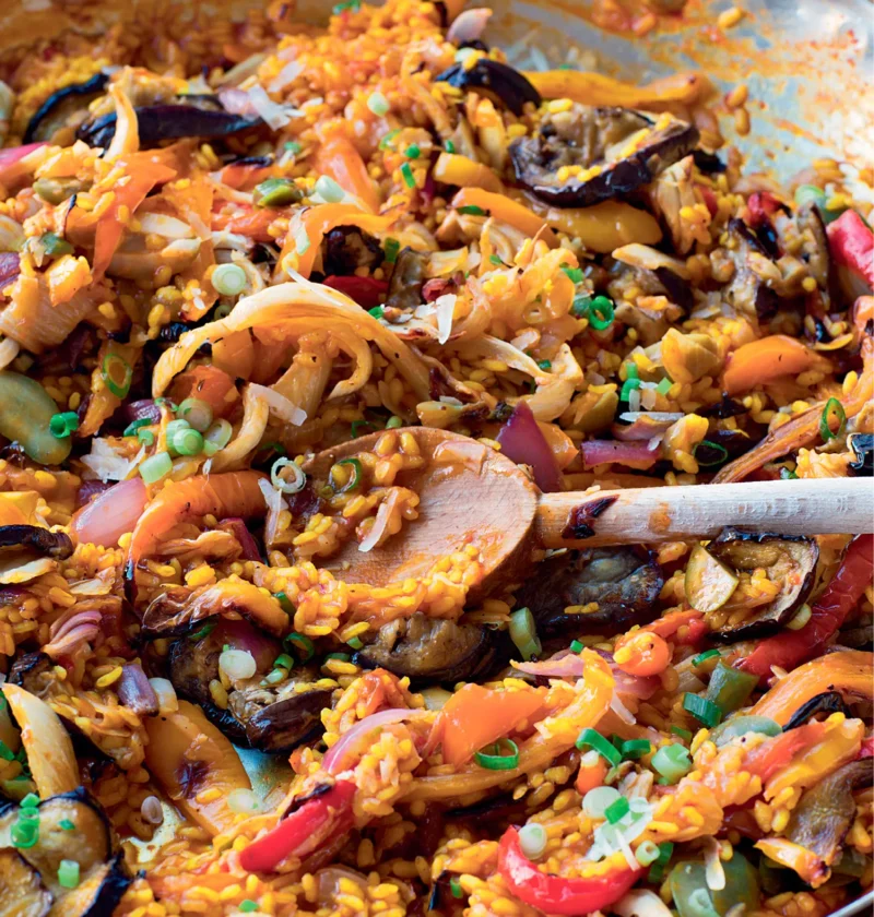Ina Garten roasted vegetable paella in a large pan with roasted bell peppers, fennel, eggplant and saffron rice