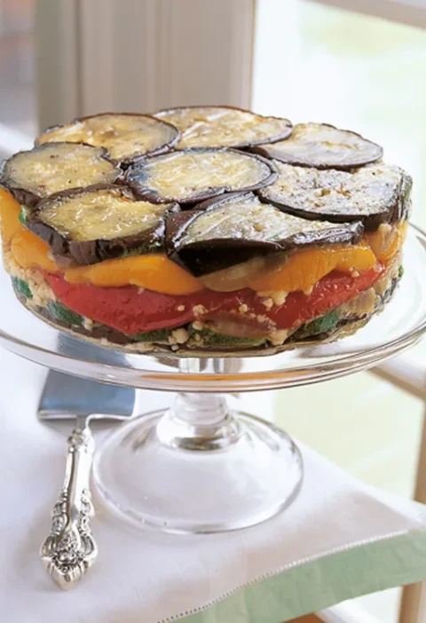 Ina Garten roasted vegetable torte with layers of eggplant, red and yellow peppers and zucchini on a glass cake stand