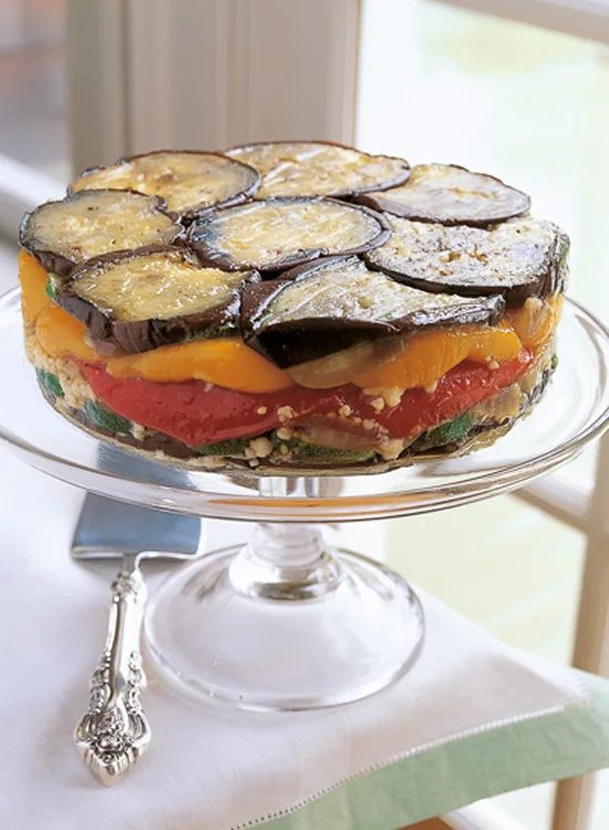 Ina Garten roasted vegetable torte with layers of eggplant, red and yellow peppers and zucchini on a glass cake stand