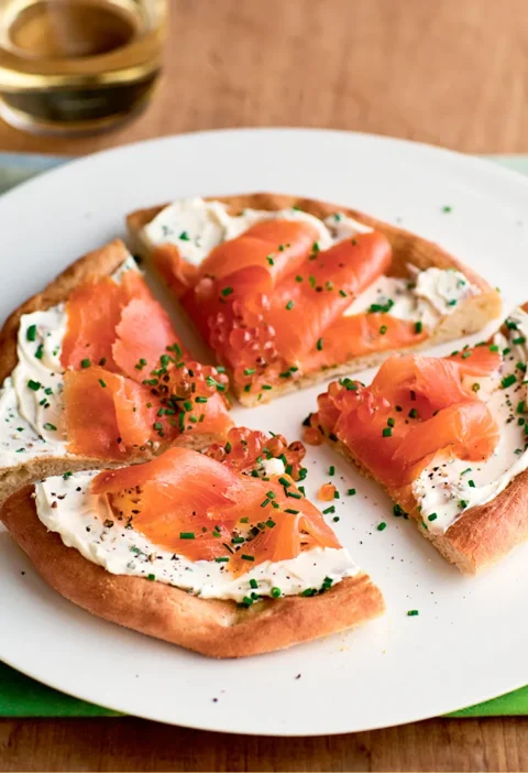 Ina Garten smoked salmon pizzas cut into wedges with mascarpone, smoked salmon and chives on a white plate