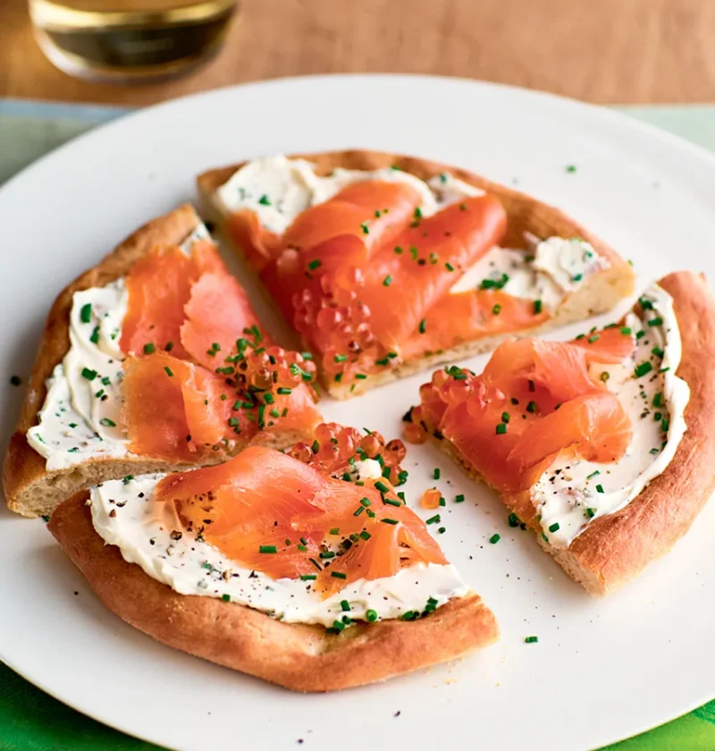 Ina Garten smoked salmon pizzas cut into wedges with mascarpone, smoked salmon and chives on a white plate