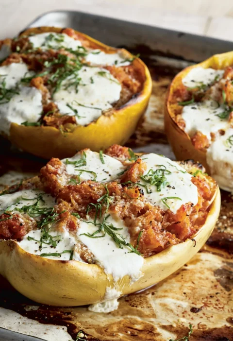 Ina Garten spaghetti squash arrabbiata in roasted squash shells topped with melted bocconcini and julienned basil on a sheet pan