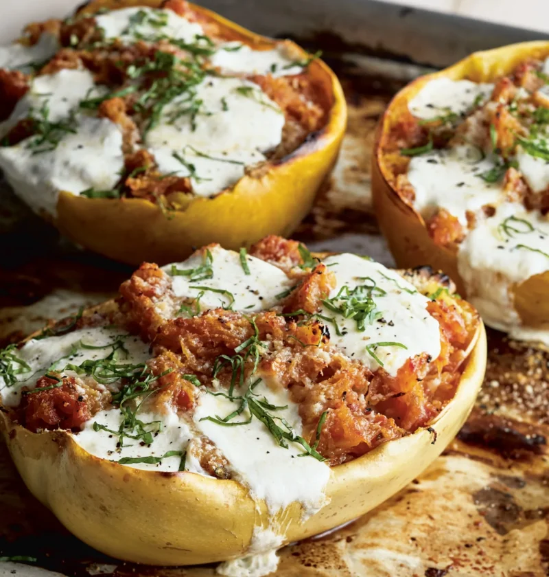 Ina Garten spaghetti squash arrabbiata in roasted squash shells topped with melted bocconcini and julienned basil on a sheet pan