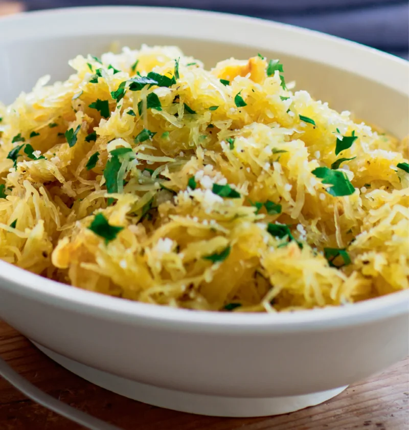 Ina Garten spaghetti squash with garlic and parmesan in a white bowl, topped with chopped parsley