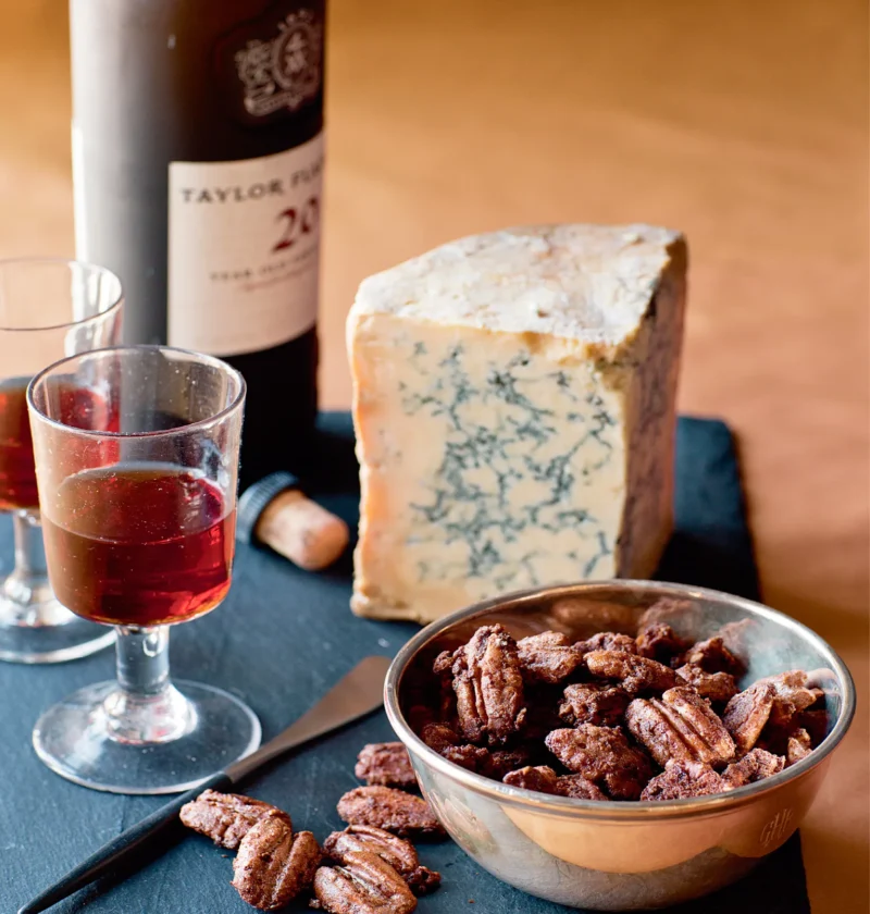 Ina Garten spiced pecans in a silver bowl beside blue cheese and a glass of port on a slate board