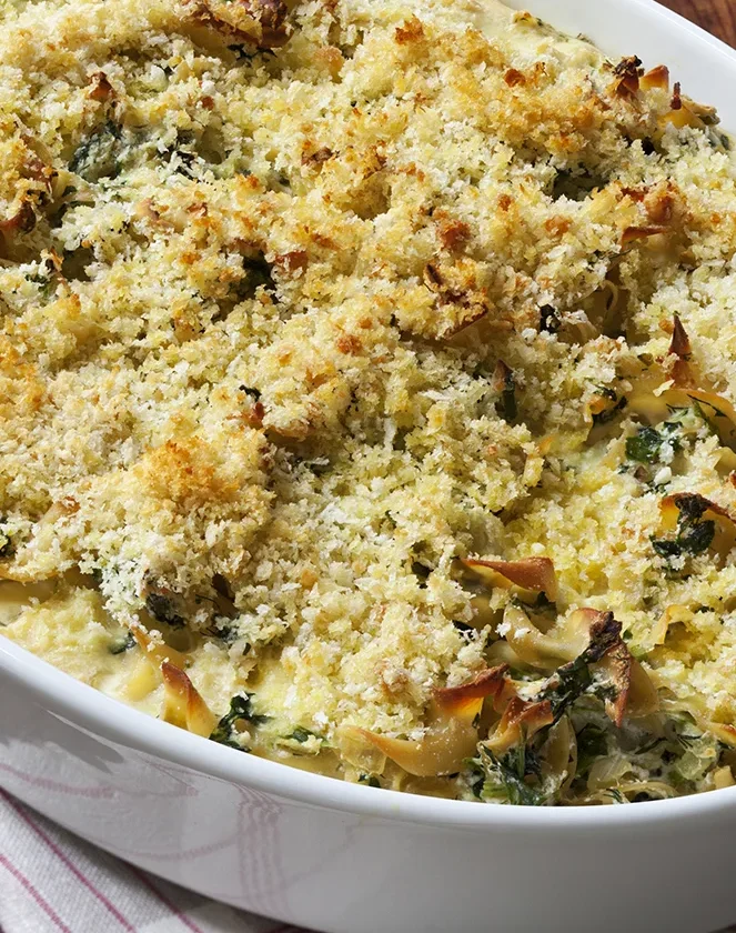 Ina Garten spinach and ricotta noodle pudding with a golden panko crust in a white oval baking dish