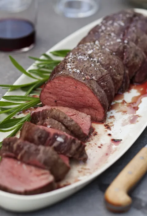 Ina Garten summer filet of beef with béarnaise mayonnaise, sliced rare tenderloin on a white platter with fresh tarragon