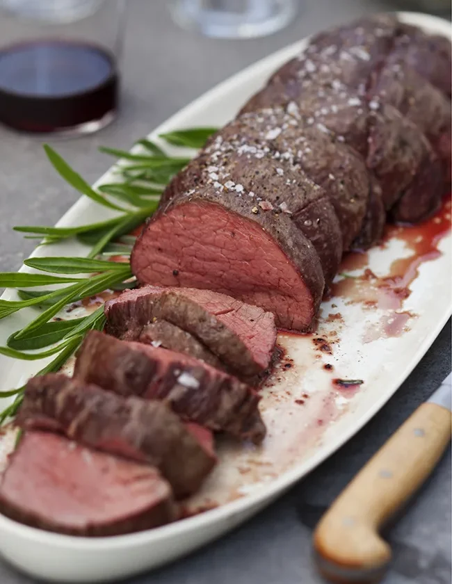 Ina Garten summer filet of beef with béarnaise mayonnaise, sliced rare tenderloin on a white platter with fresh tarragon
